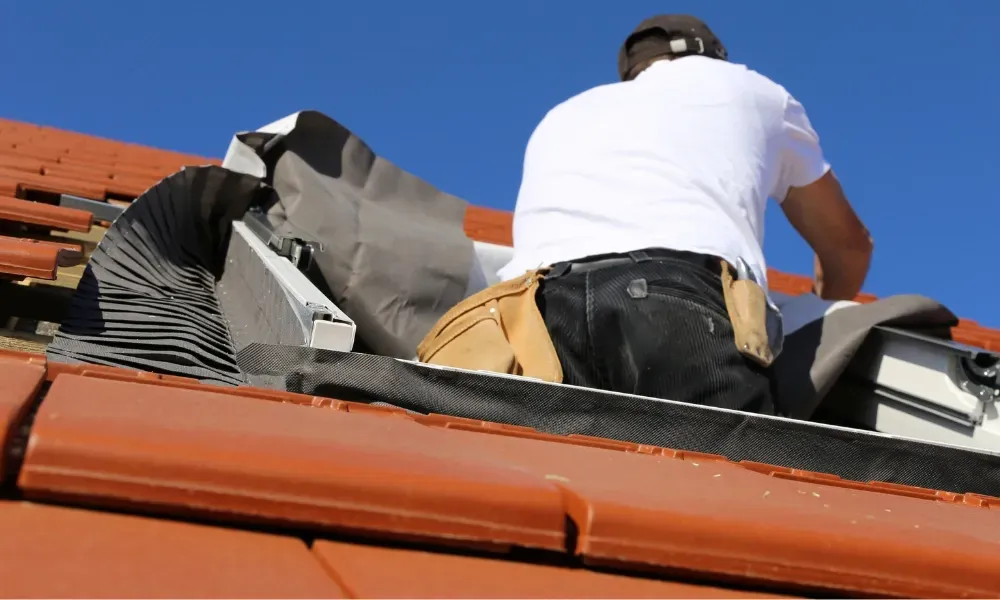 Black vented skylight on terracotta tile roof under blue sky — roofing services Palm Springs CA