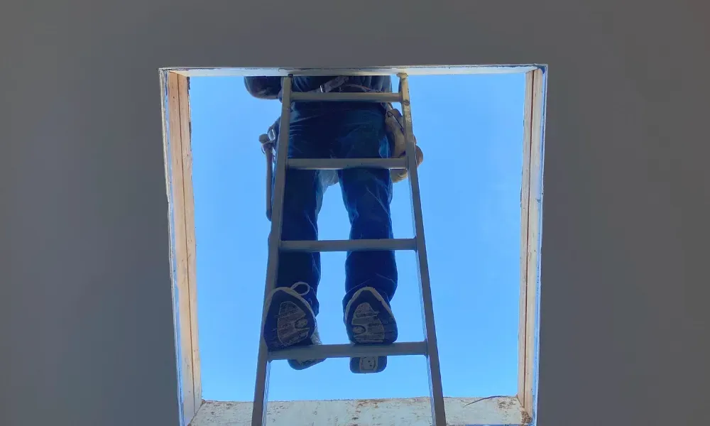 Close-up of pneumatic nail gun fastening new asphalt shingles — how do you install roof shingles