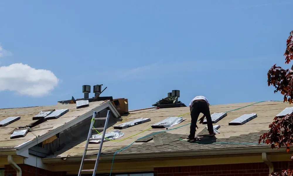 Hand lifting damaged shingle revealing gap at eave — what are signs of roof damage after a storm