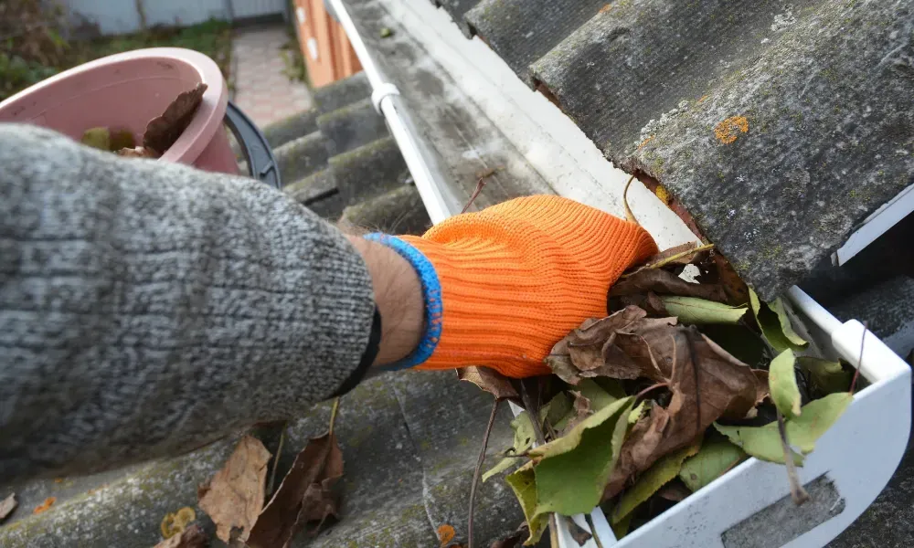 Worker power washing red clay tile roof to remove moss and debris — how to remove moss from roof