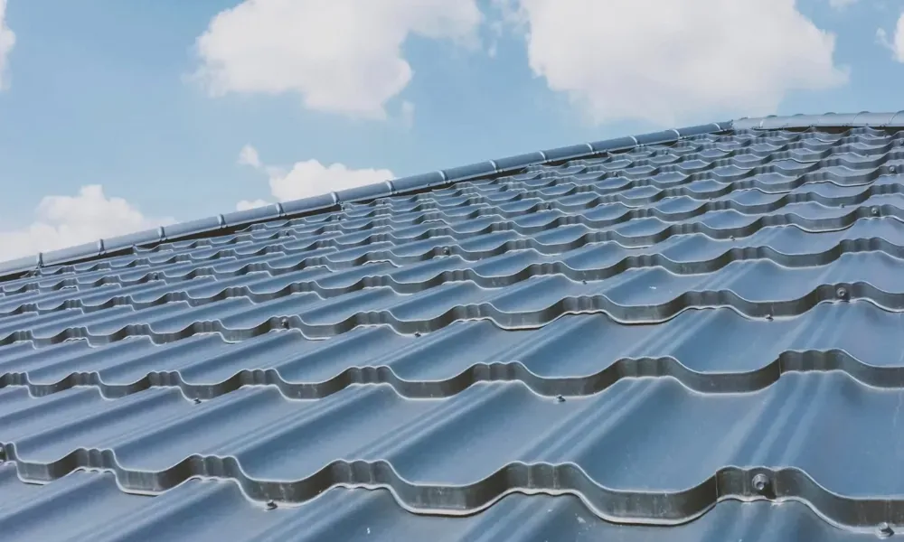 Gloved hand operating nail gun fastening brown asphalt shingles — how do you install roof shingles