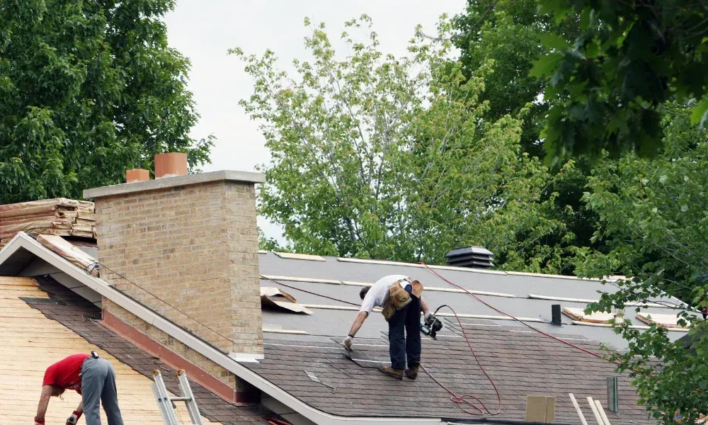Worker power washing red clay tile roof to remove moss and debris — how to remove moss from roof
