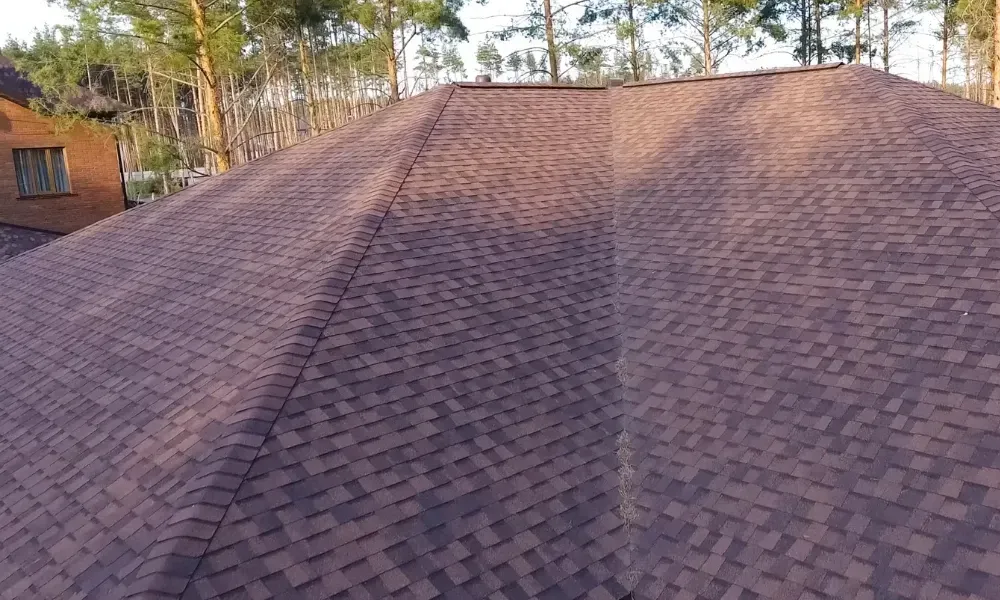 Hand lifting damaged shingle revealing gap at eave — what are signs of roof damage after a storm