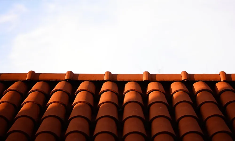 Gloved hand operating nail gun fastening brown asphalt shingles — how do you install roof shingles