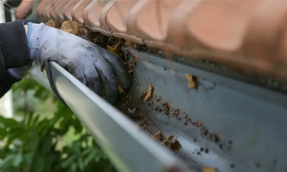 Worker power washing red clay tile roof to remove moss and debris — how to remove moss from roof
