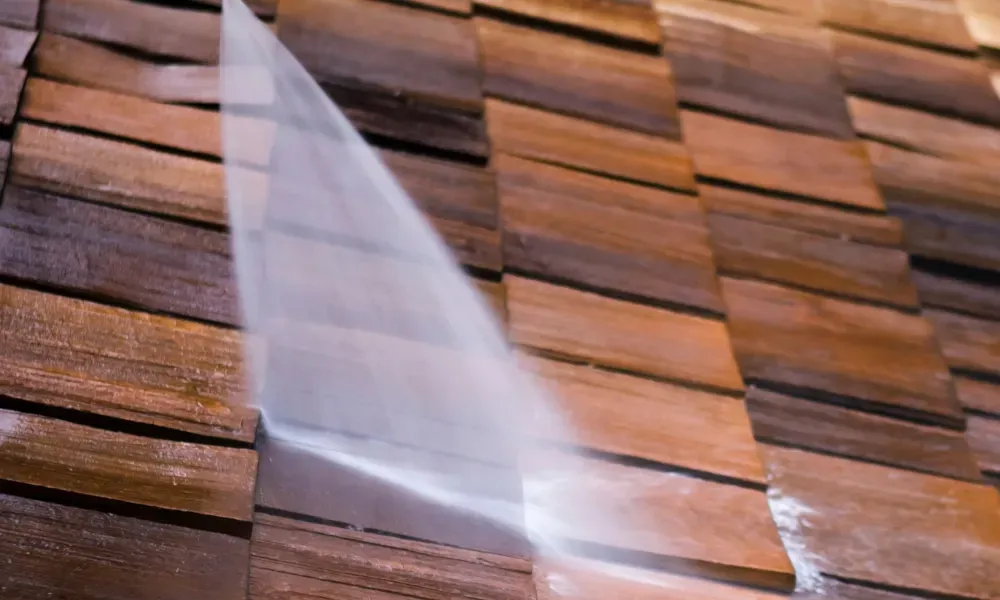 Worker power washing red clay tile roof to remove moss and debris — how to remove moss from roof