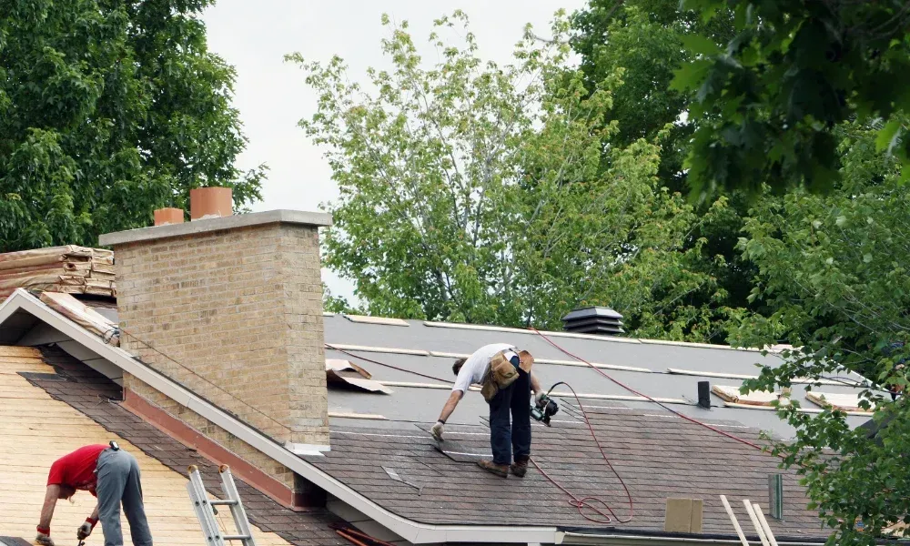 Hand lifting damaged shingle revealing gap at eave — what are signs of roof damage after a storm
