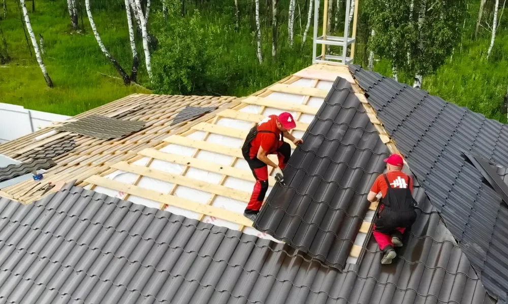 Gloved hand operating nail gun fastening brown asphalt shingles — how do you install roof shingles