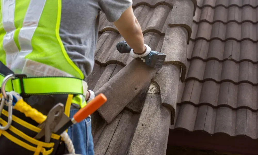 Hand lifting damaged shingle revealing gap at eave — what are signs of roof damage after a storm