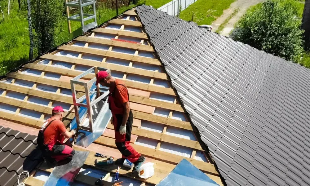 Gloved hand operating nail gun fastening brown asphalt shingles — how do you install roof shingles
