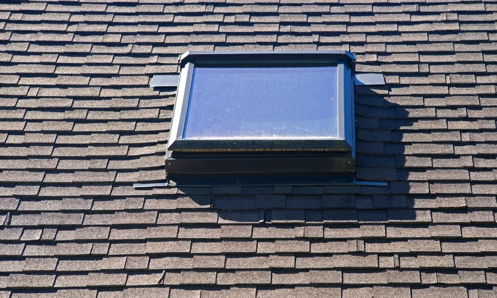Black vented skylight on terracotta tile roof under blue sky — roofing services Palm Springs CA