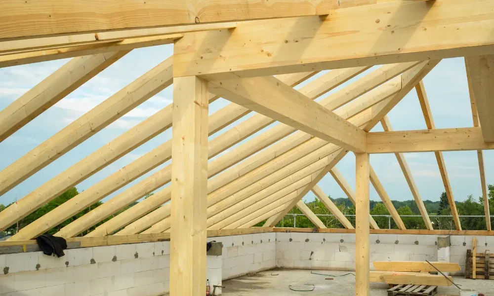 Gloved hand operating nail gun fastening brown asphalt shingles — how do you install roof shingles