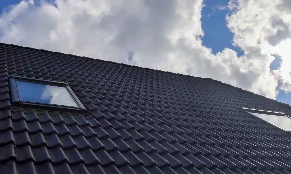 Black vented skylight on terracotta tile roof under blue sky — roofing services Palm Springs CA