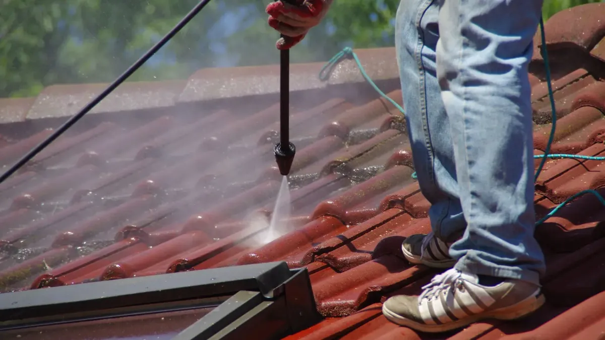 Scupper mouth packed with debris holding standing water on a flat roof — who cleans roofs near me
