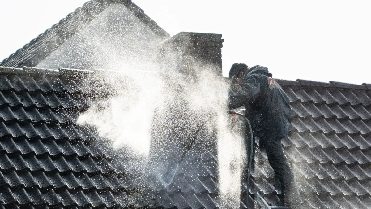 Scupper mouth packed with debris holding standing water on a flat roof — who cleans roofs near me