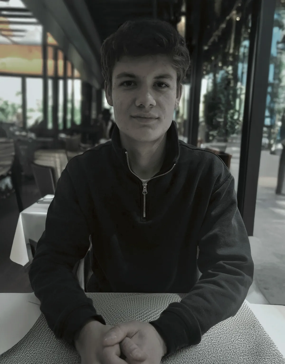 Porträt eines sympathischen, jungen Gründers mit Brille, lächelt freundlich, modernes Büro im Hintergrund, Teammitglieder arbeiten an Laptops, helle Atmosphäre, Fokus auf persönliche Beratung und digitale Kompetenz, Frankfurt