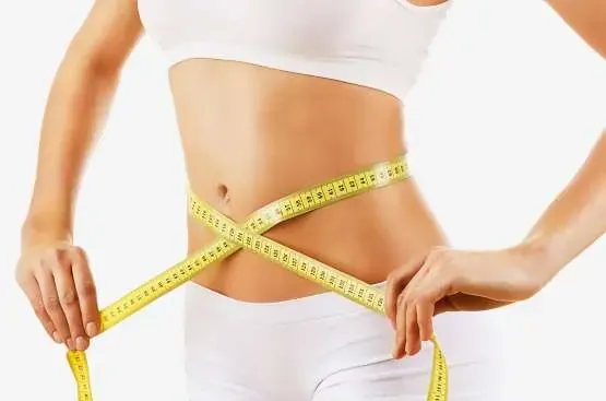 Woman measuring her waist, symbolizing weight loss and the role of hypnosis in emotional eating.