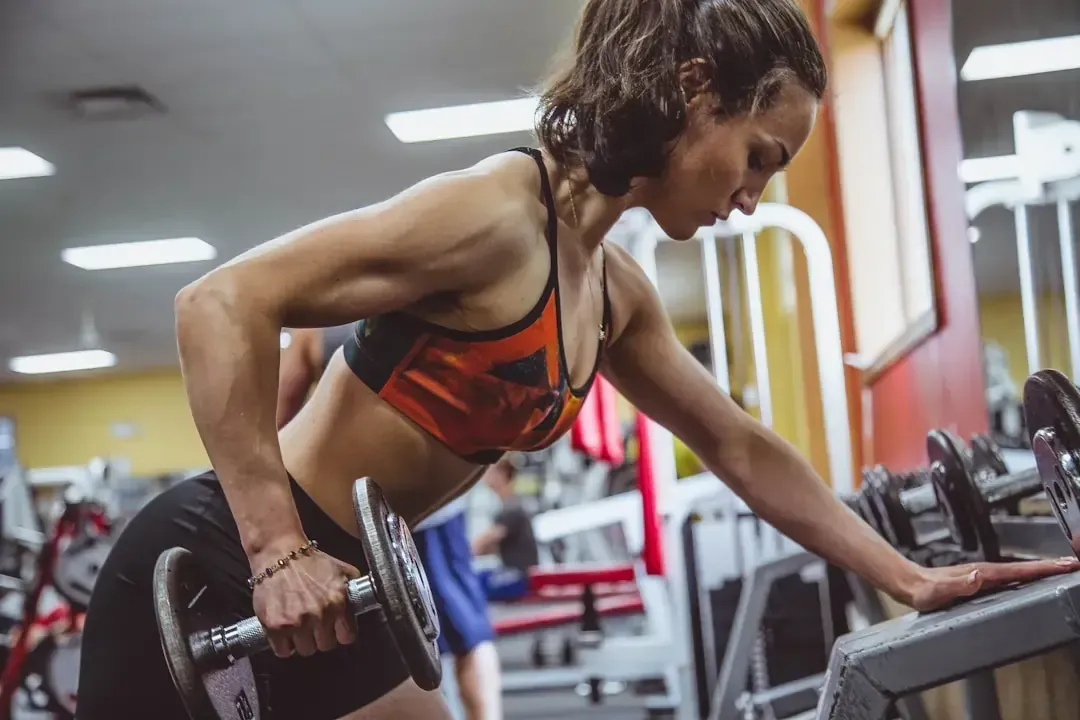 Woman exercising in a gym, symbolizing strength and balance achieved through hypnosis and breathwork.