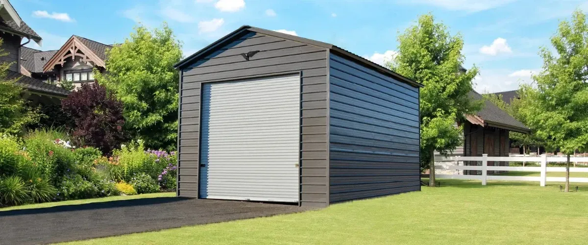 Gray metal garage with roll-up door on blacktop driveway