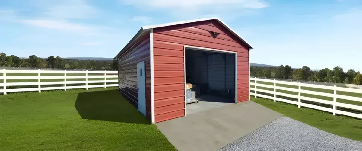 Red metal garage building with white trim and roll-up door on a farm property