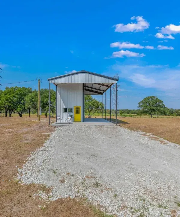 Metal workshop building with gravel driveway on rural property