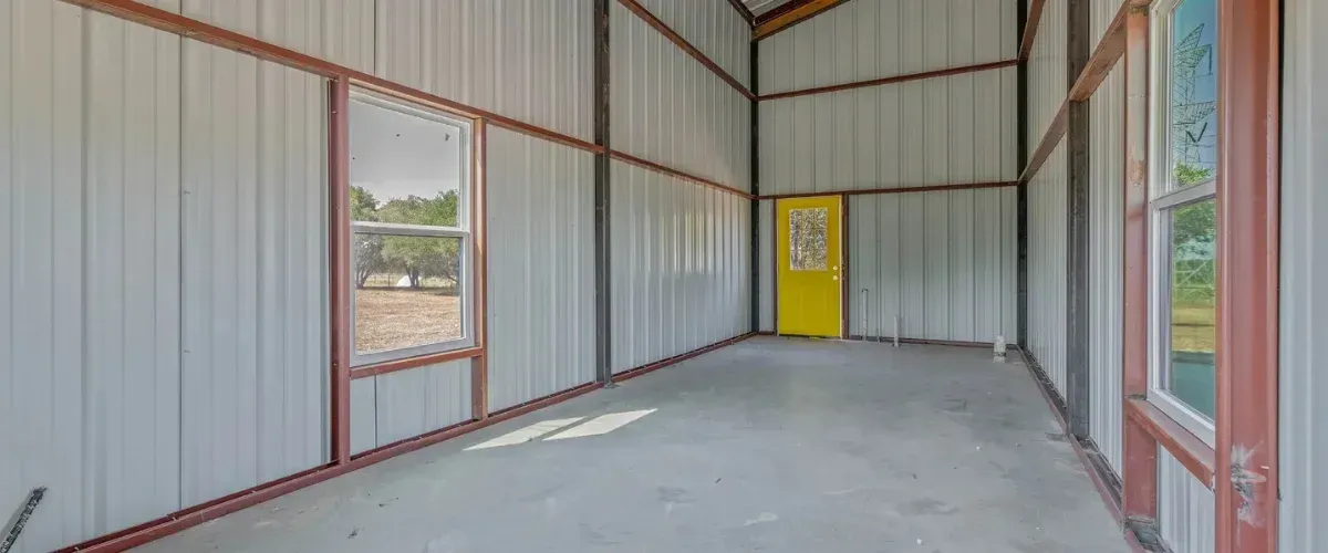 Interior of metal building with yellow door and concrete floor