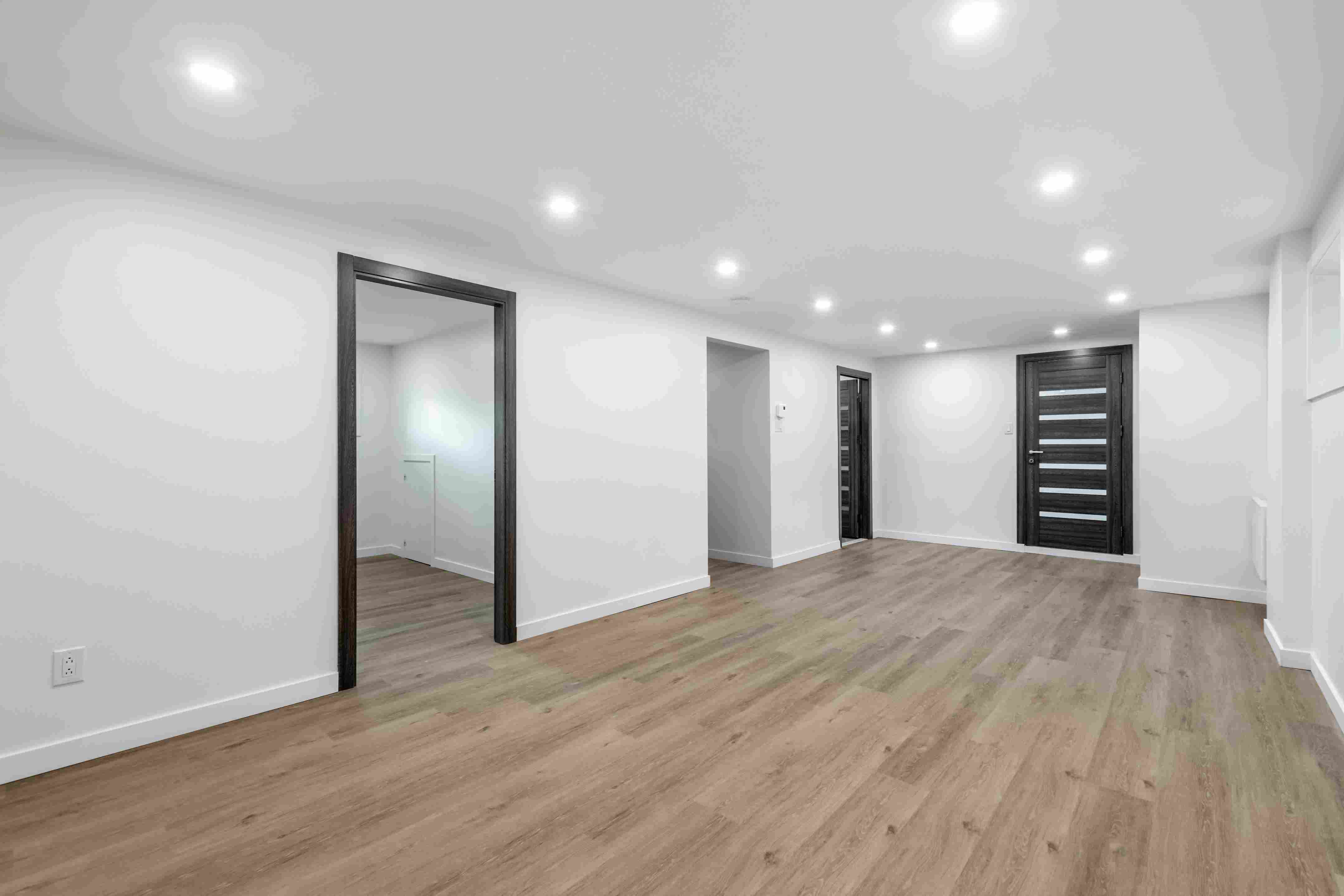Finished basement space in Edmonton with modern flooring, recessed lighting and multiple room access