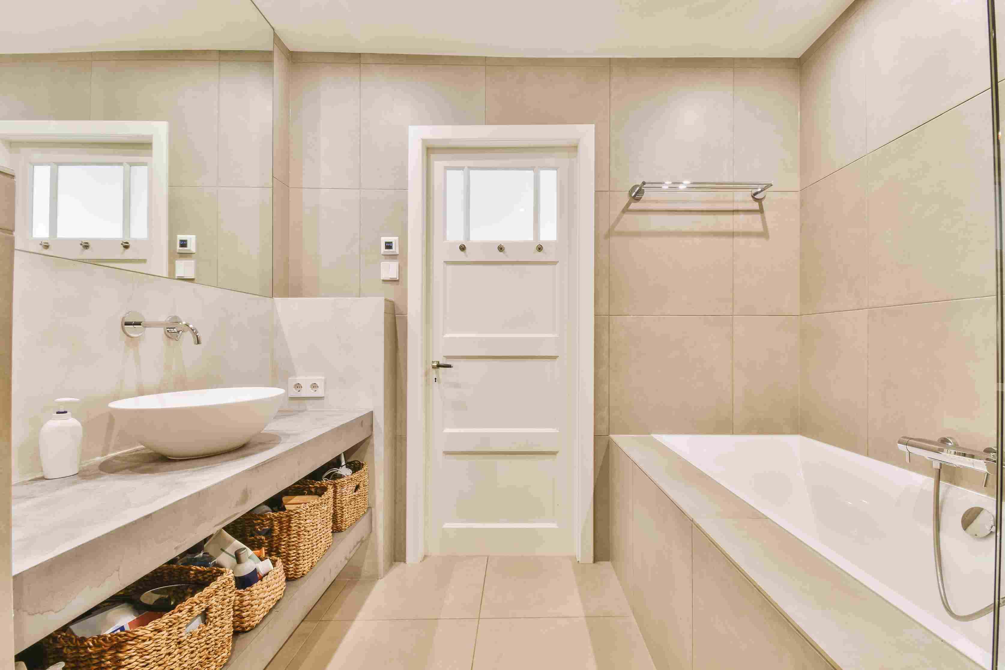 Bathroom renovation in Edmonton with modern bathtub, vanity sink, tiled walls and storage baskets