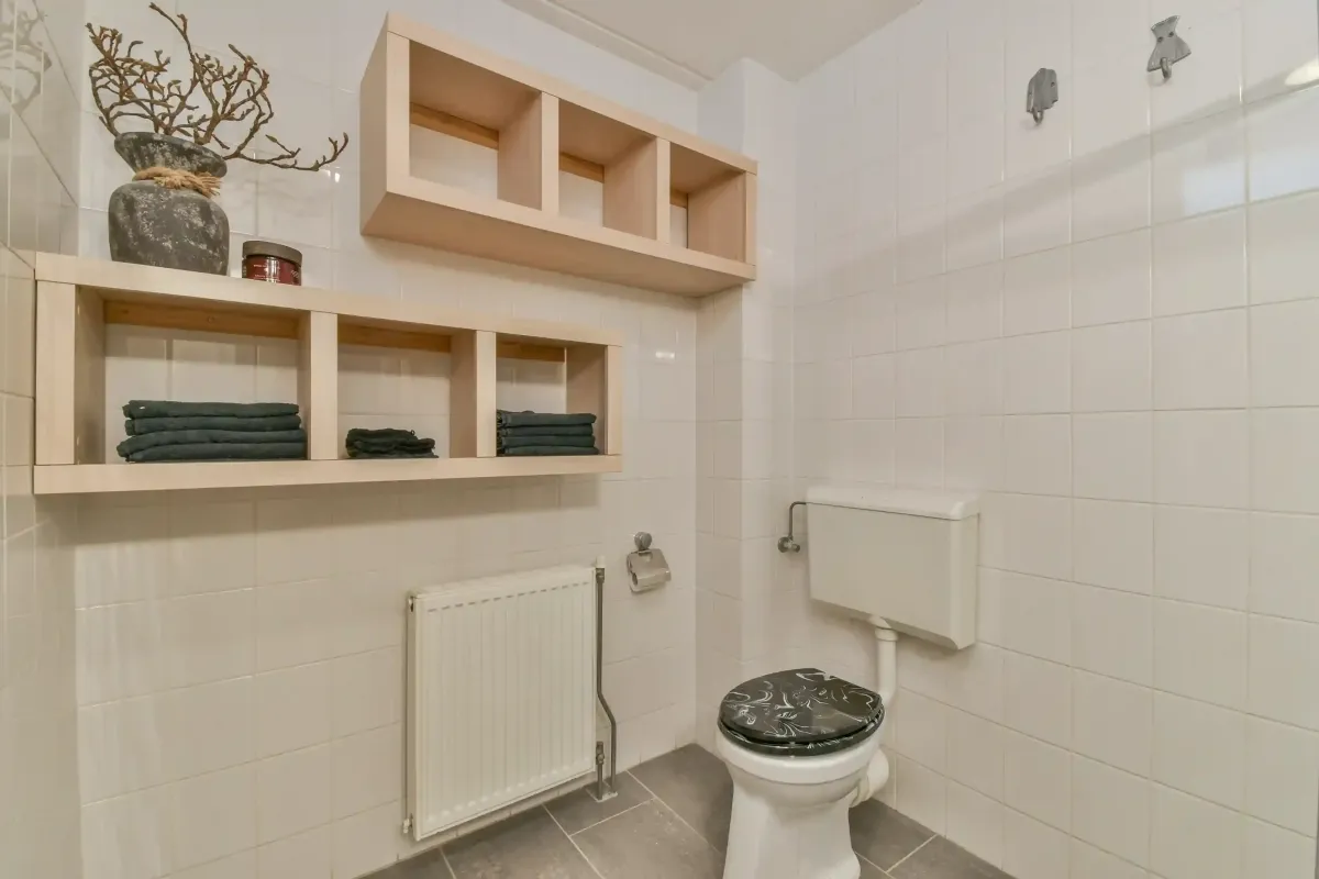 Small bathroom renovation in Edmonton with toilet, wall shelving storage and tiled walls