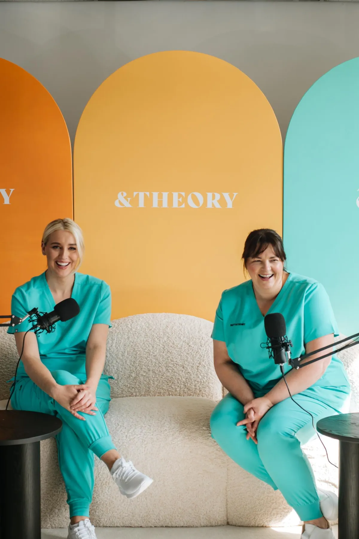 Odessa Turner and Victoria Holmes at on the sofa laughing whilst doing the podcst