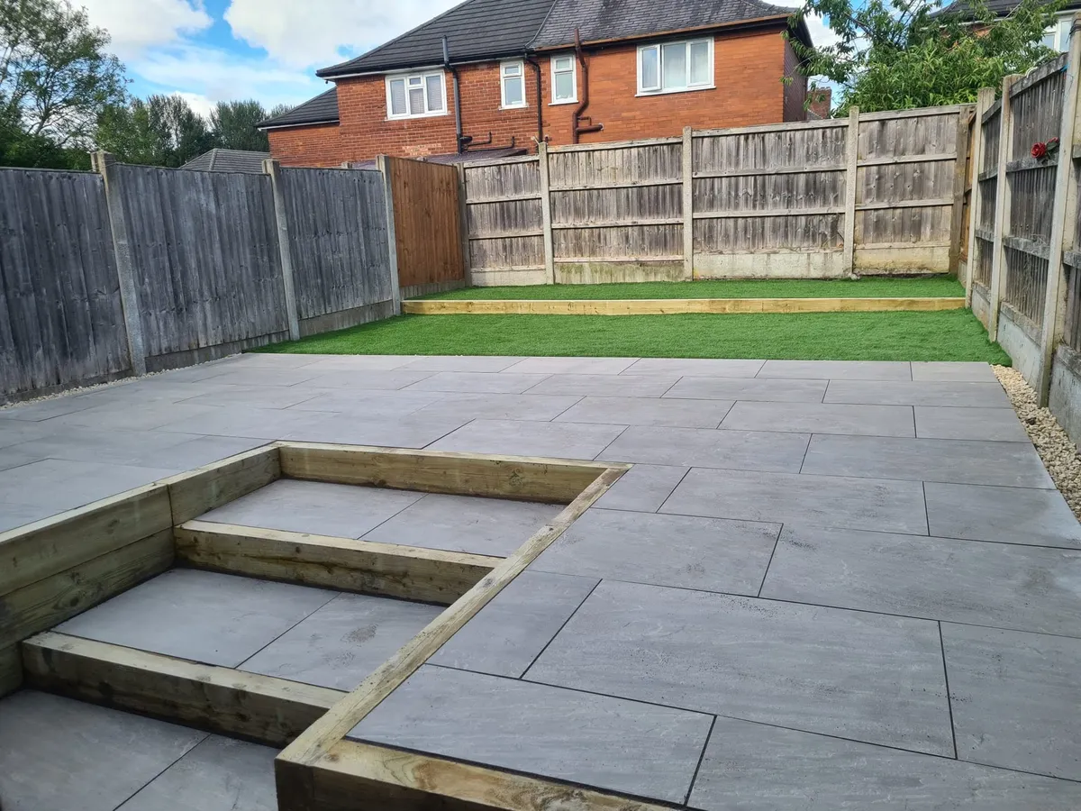 Large grey slate patio with timber steps and lawn in a Manchester garden