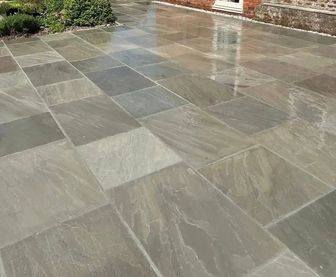 Sandstone paved patio with raised timber sleeper beds and a garden shed in Manchester