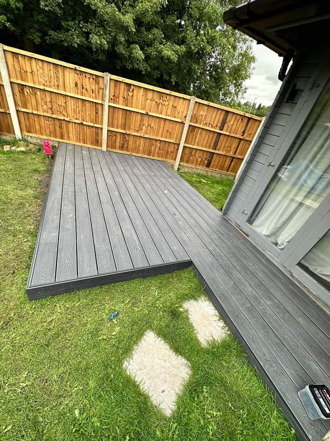 Grey composite decking path beside a lawn in a Manchester garden