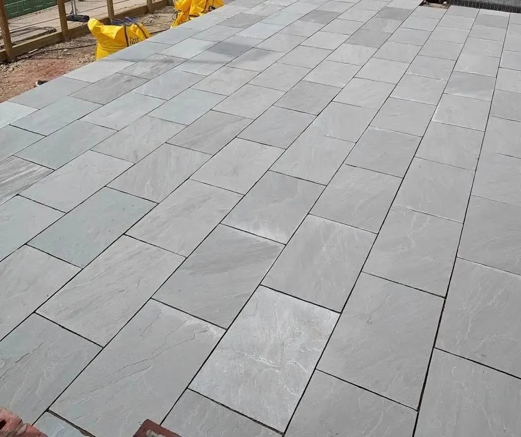 Grey composite decking with steps and newly laid turf beside a house extension in Manchester