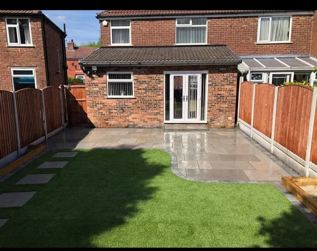 Sandstone paved patio with raised timber sleeper beds and a garden shed in Manchester