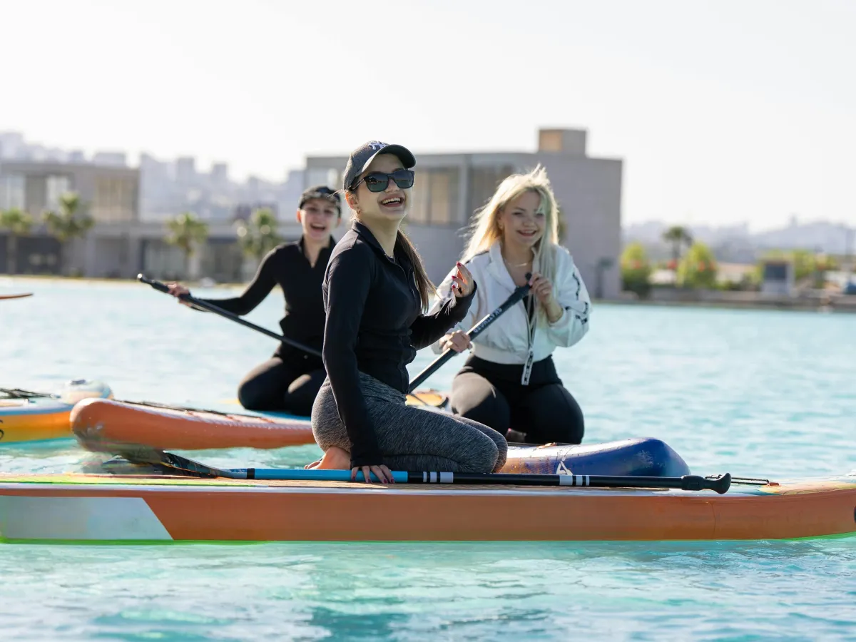Women paddleboarding together on bright blue water – bold travel retreat for active women over 40