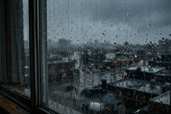 Overthinking ruining my life, rain on a city window at dusk