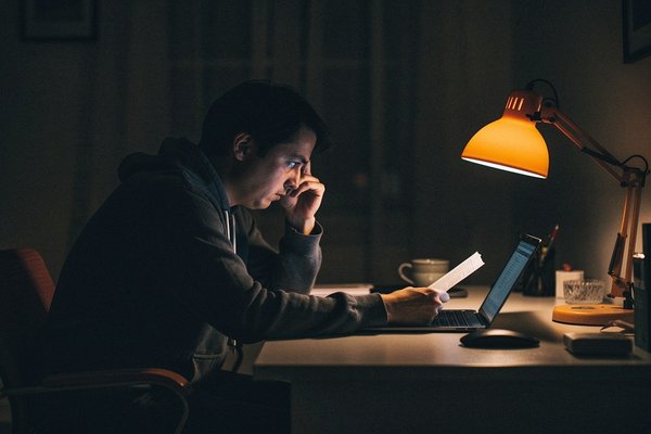 Overthinking decisions already made: person alone at a desk at night, caught in a persistent decision-revisiting loop