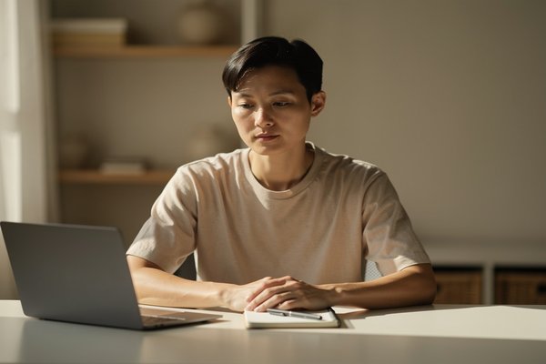 Guided overthinking session cost and value: person alone at a desk with a laptop in quiet deliberation, considering an internal decision