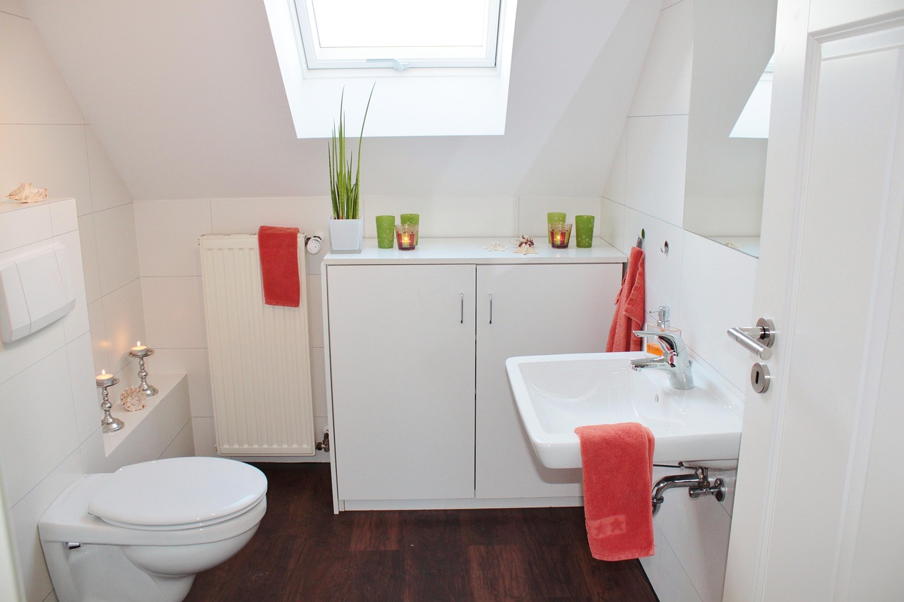 white cupboard, white toilet, white sink in an attic bathroom that has a slanted ceiling