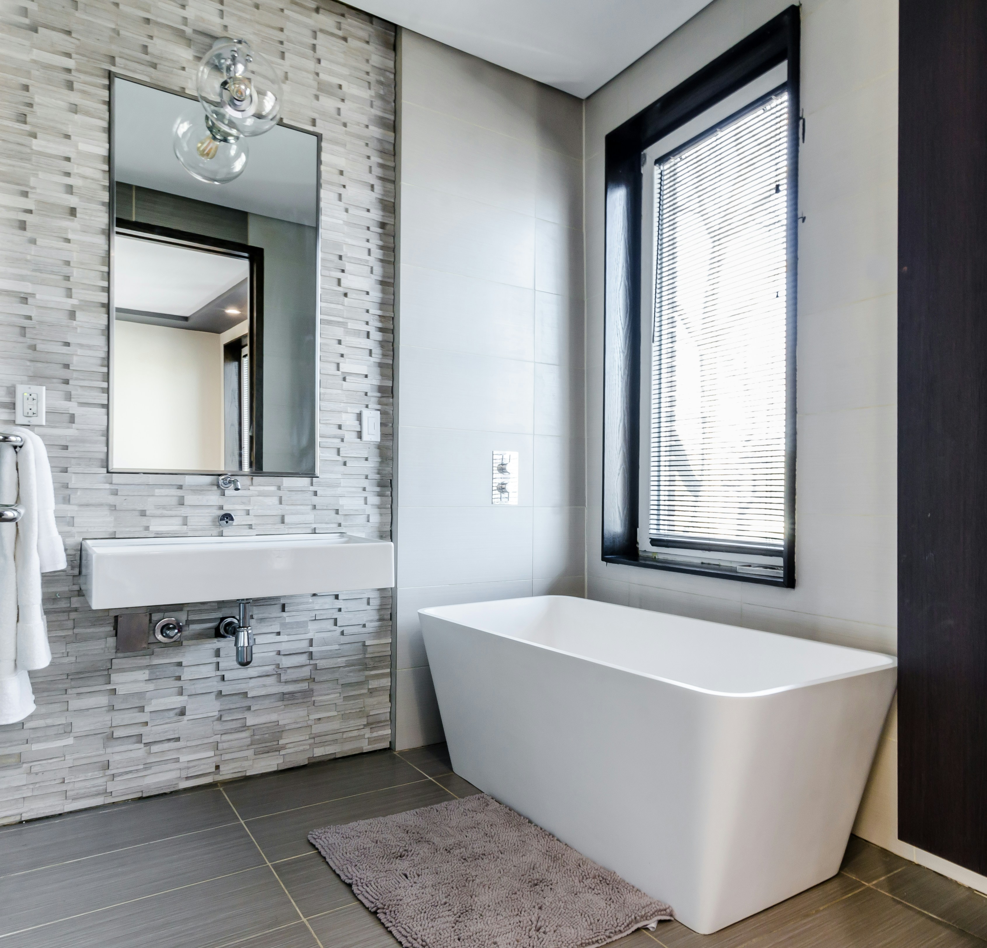 grey theme bathroom with a bathtub and sink and large silver framed mirror