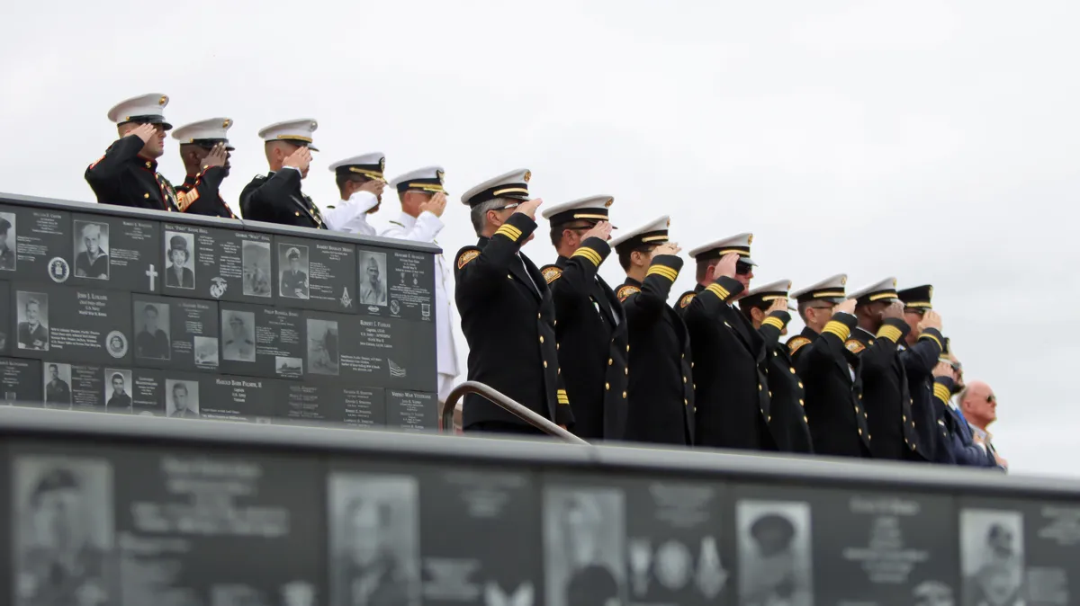 Service members salute beside the veteran plaque walls at Mt. Soledad National Veterans Memorial