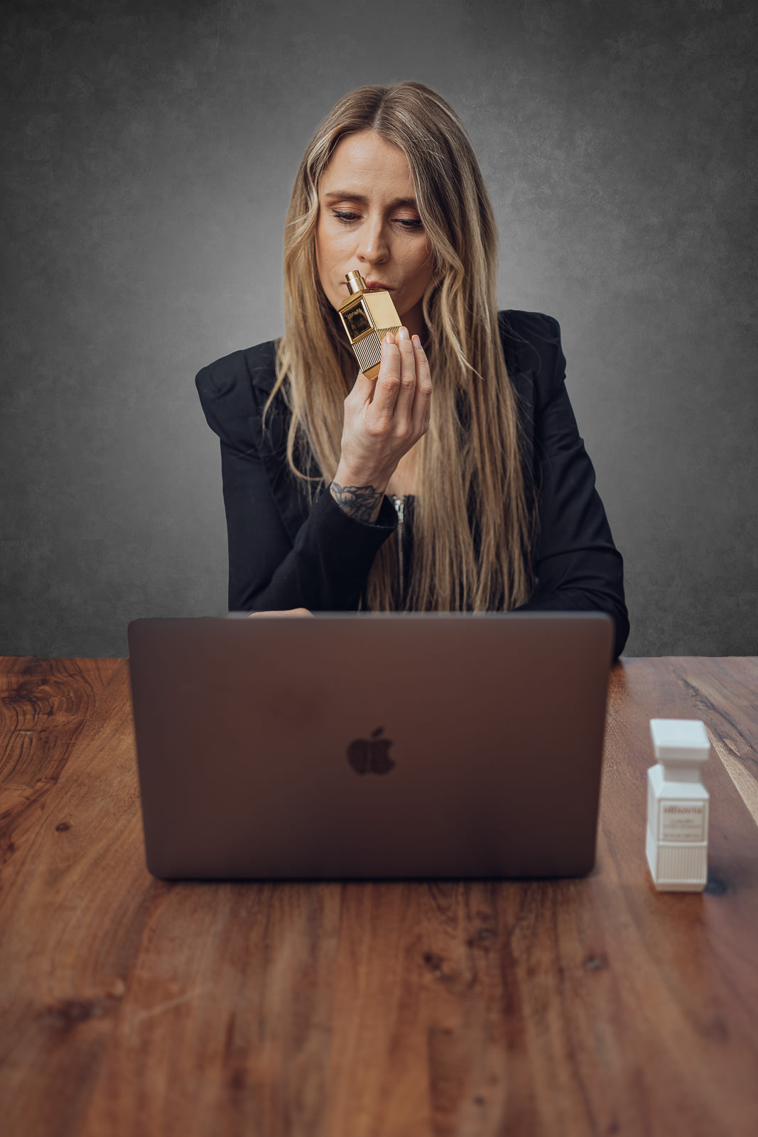 Personal Branding Portrait einer Frau mit Parfum und Laptop am Holztisch