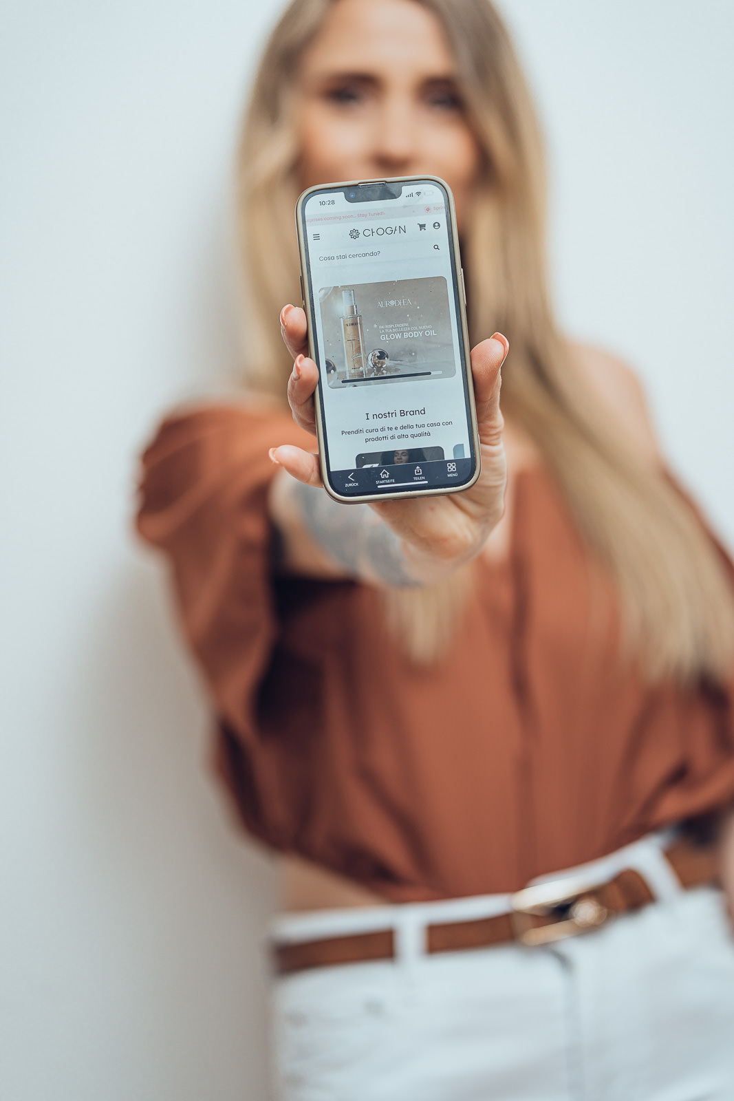 Personal Branding Foto mit Smartphone im Fokus und Frau im weichen Hintergrund