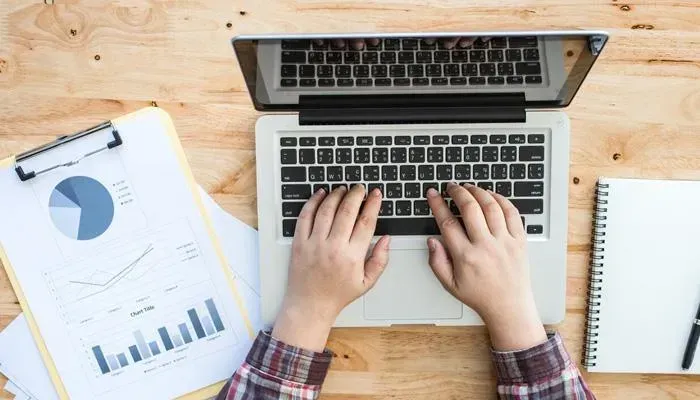 Hands typing on laptop with analytics graphs for dental SEO