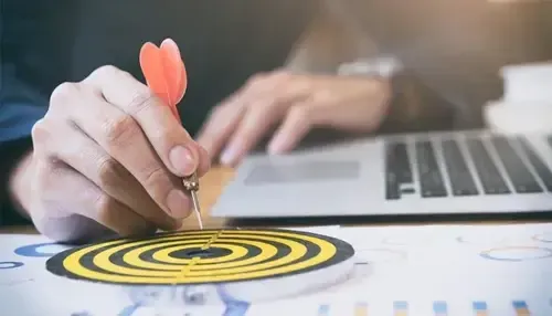 Hand throwing dart at target board for dental marketing strategy