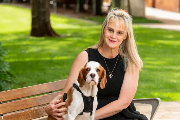 Julie McCracken sitting outdoors beside her dog, smiling gently, capturing a calm, grounded presence that reflects balance, warmth, and authentic leadership.