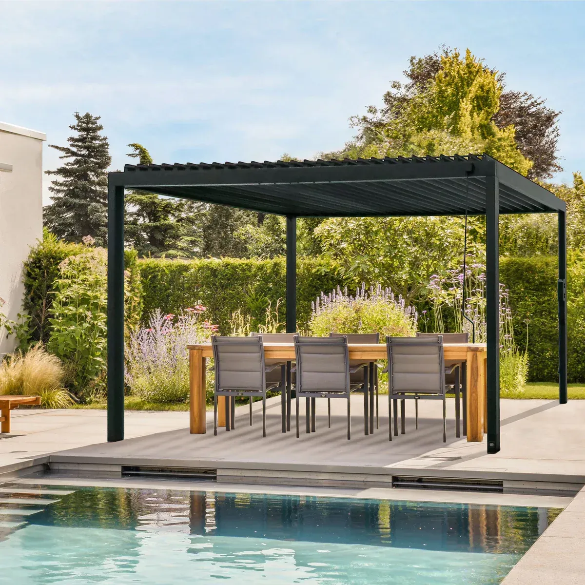 Modern gray metal pergola on a patio with outdoor seating and tropical landscaping.