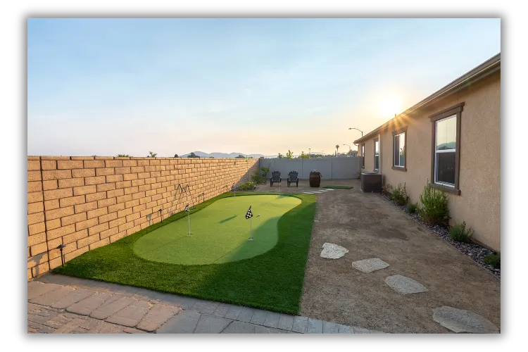 Backyard artificial turf lawn with a stepping-stone path, fire pit seating area, and block wall in San Diego