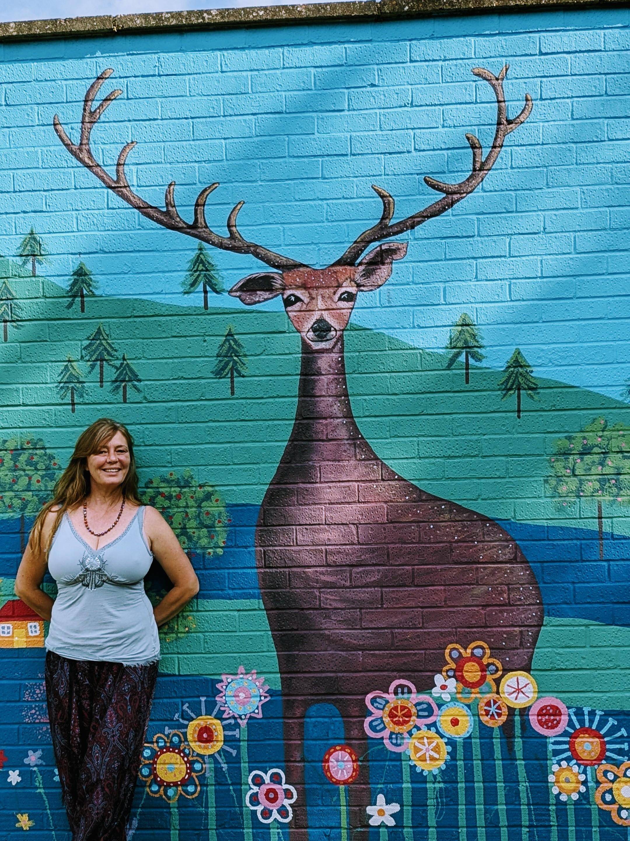 Janine Tonkin beside the central stag in the Wild and Wonderful community mural, inspired by Bracknell's local deer, woodland, historic apple orchards, and native bluebell landscapes.